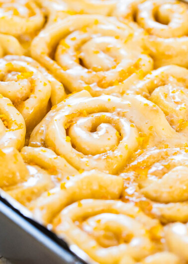 Freshly baked cinnamon rolls in a pan, covered with icing.