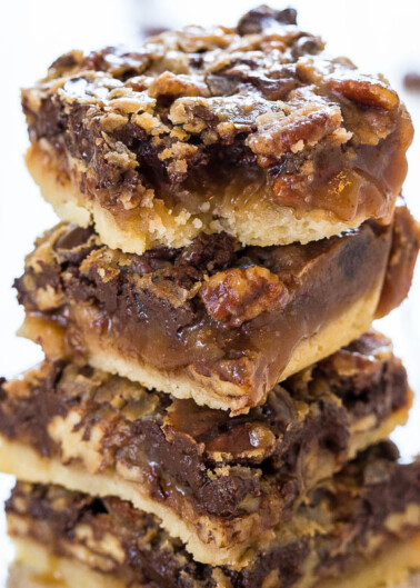 A stack of pecan pie bars with a crumbly topping and chocolate drizzle.