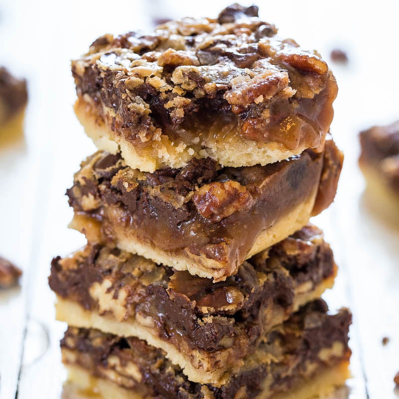 A stack of pecan pie bars with a crumbly topping and chocolate drizzle.