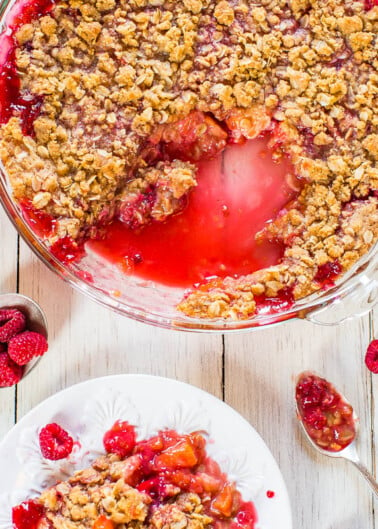 A freshly baked peach and raspberry crisp with a scoop served on a plate.
