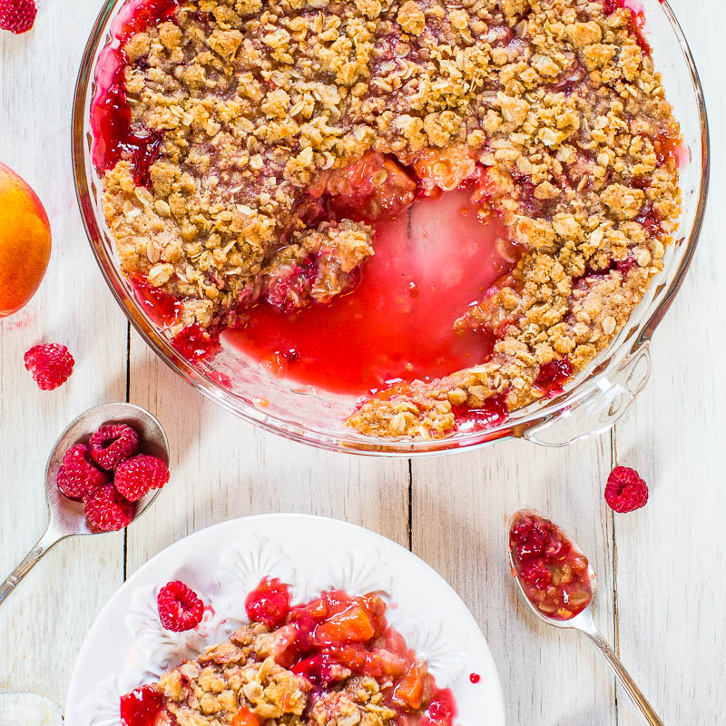 A freshly baked peach and raspberry crisp with a scoop served on a plate.