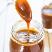 Salted Caramel Sauce in a jar with a spoon lifting a scoop.
