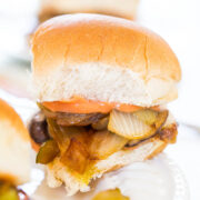 A close-up of a slider with grilled onions and pickles.