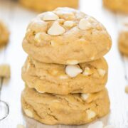 A stack of white chocolate chip cookies on a light wooden surface.