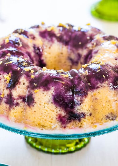 A brightly colored blueberry lemon bundt cake on a glass stand.