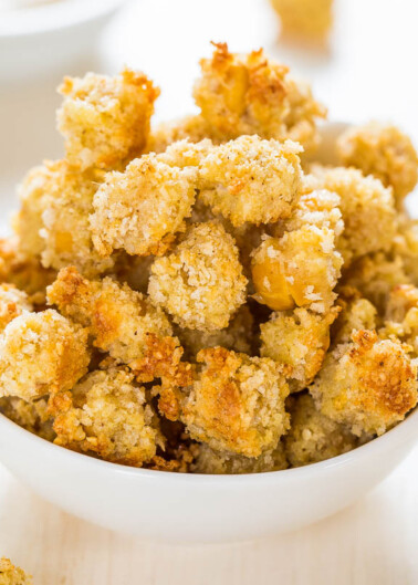 A bowl of crispy breaded cauliflower bites on a wooden surface.