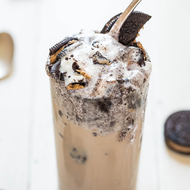 A cookies and cream milkshake garnished with whipped cream and a whole oreo cookie on top.