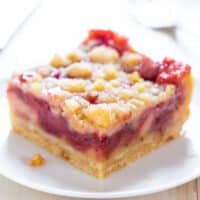 A slice of crumb-topped raspberry pie on a white plate.