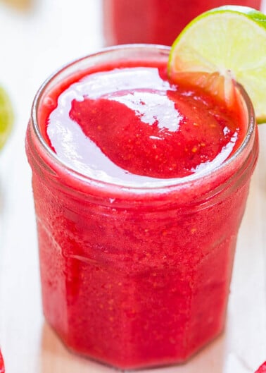 A refreshing glass of strawberry slush topped with a lime slice.