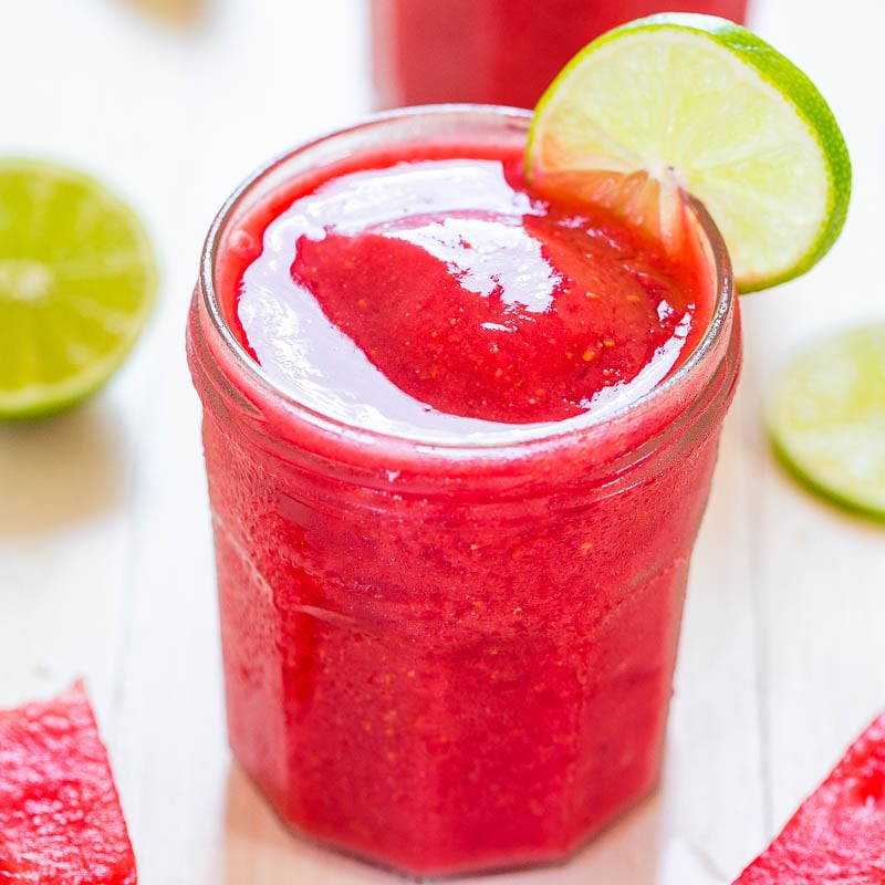 A refreshing glass of strawberry slush topped with a lime slice.