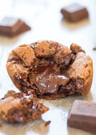 A molten chocolate chip cookie with a gooey center, surrounded by pieces of chocolate.