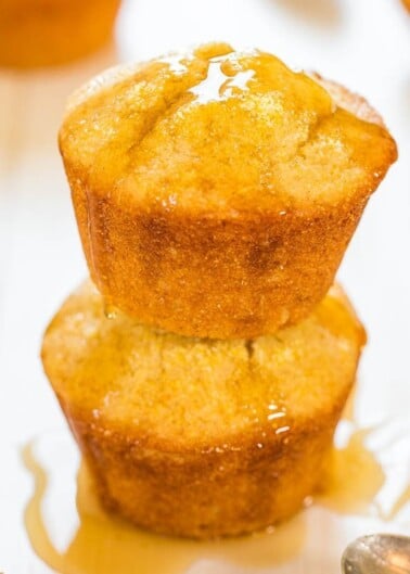 Two golden-brown muffins stacked with honey drizzled on top.