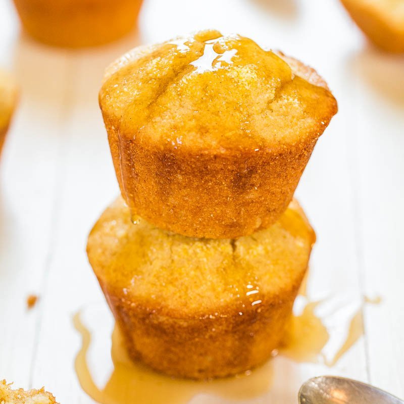 Two golden-brown muffins stacked with honey drizzled on top.
