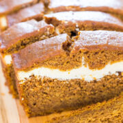A close-up image of a sliced pumpkin cream cheese loaf on a wooden surface.