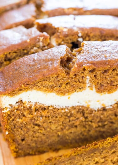 A close-up image of a sliced pumpkin cream cheese loaf on a wooden surface.