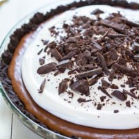 A chocolate pie with whipped cream and chocolate shavings on top.