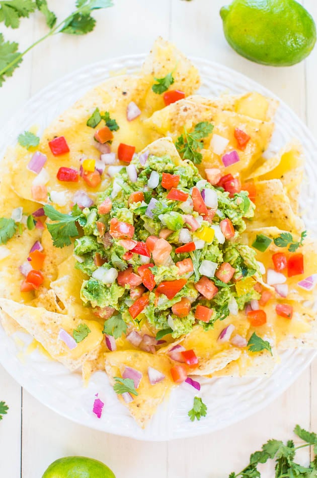 Loaded Guacamole Nachos - Fresh, easy homemade guac on top of cheesy chips is totally irresistible! These disappear fast - so good!!