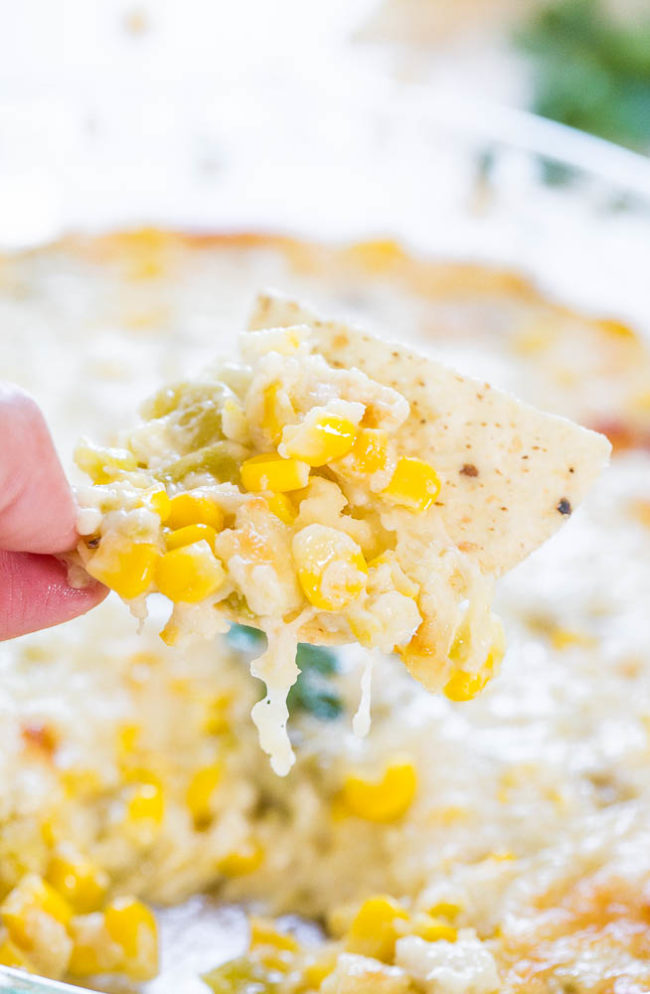 Tortilla chip being dipped into Hot Cheesy Corn Dip