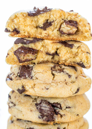 A stack of chocolate chip cookies with one cookie broken in half at the top.
