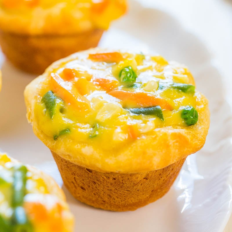 Mini vegetable quiches on a white surface.