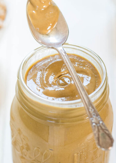 A jar of creamy peanut butter with a spoon inserted into it.