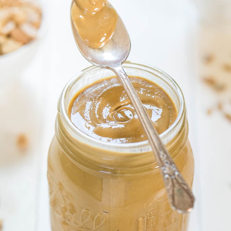 A jar of creamy peanut butter with a spoon inserted into it.