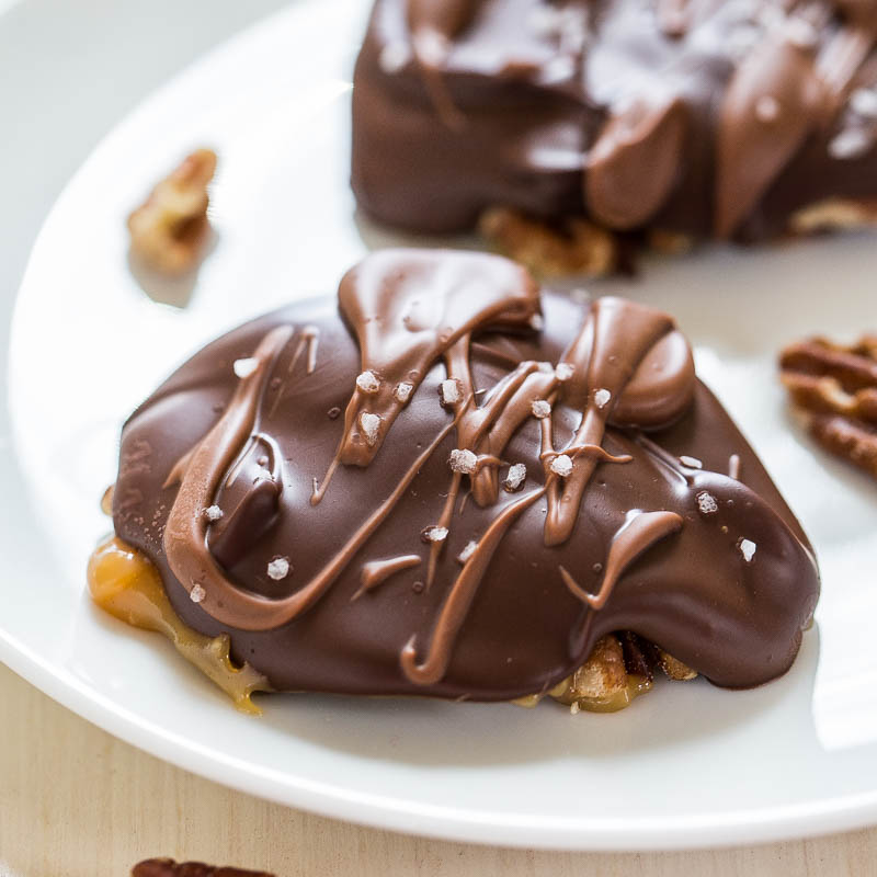 Chocolate-covered caramel nut candies on a white plate.