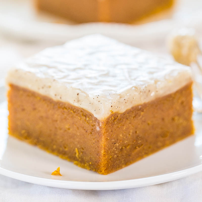 A slice of frosted pumpkin cake on a white plate.