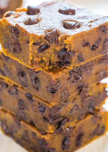 A stack of chocolate chip pumpkin bread slices on a wooden surface.