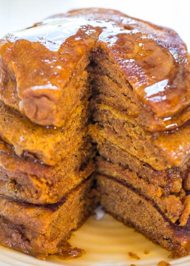 A stack of pumpkin pancakes with syrup on a white plate.
