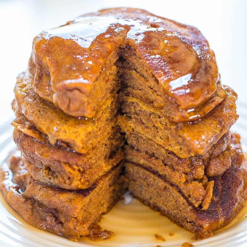 A stack of pumpkin pancakes with syrup on a white plate.
