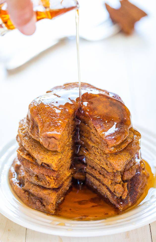 maple syrup being poured over a stack of pumpkin spice pancakes 