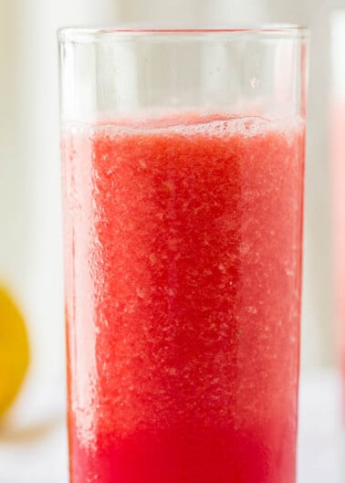 Two glasses of red slushie with a blurred background.