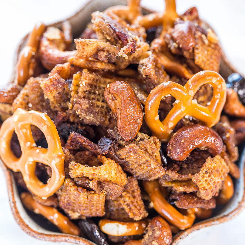 A close-up of a snack mix containing pretzels, nuts, and seasoned bread pieces.