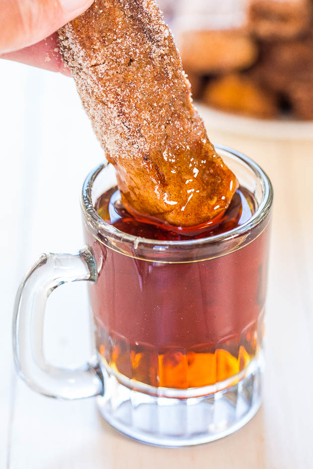 dipping Cinnamon French Toast Stick into glass of maple syrup