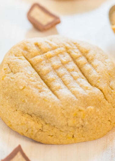 A freshly baked peanut butter cookie displayed on a light wooden surface.
