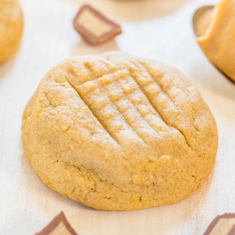 A freshly baked peanut butter cookie displayed on a light wooden surface.