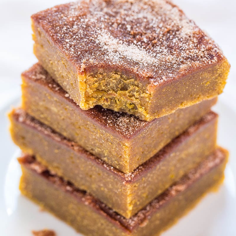 A stack of pumpkin bars dusted with powdered sugar on a white plate.