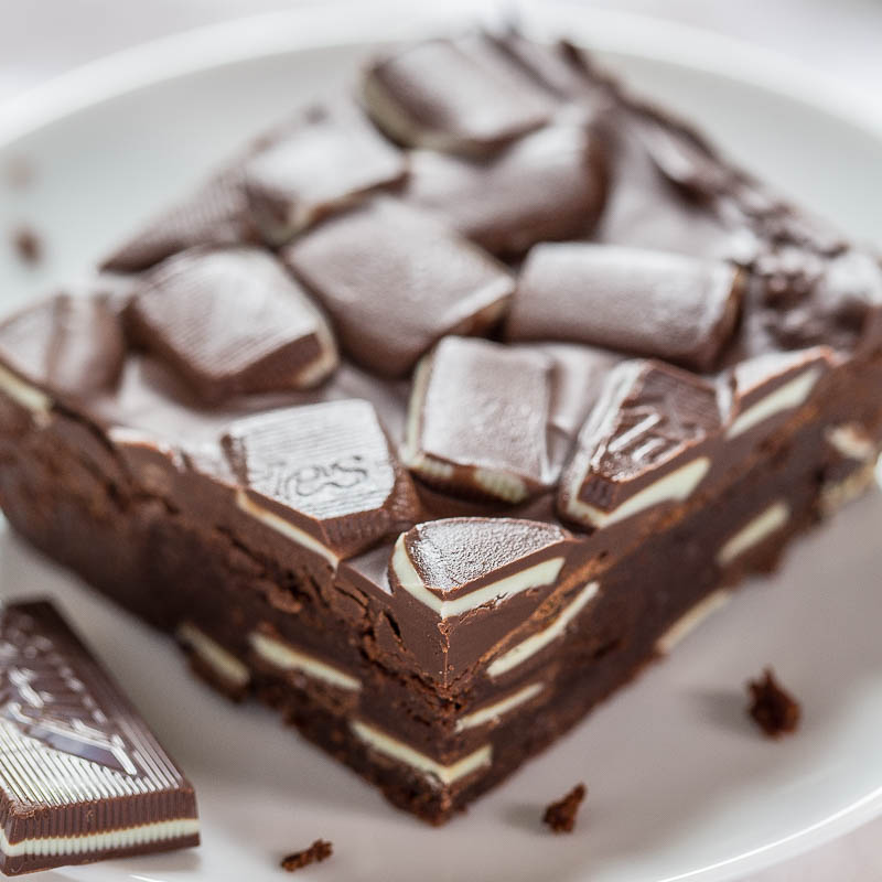 A rich chocolate brownie topped with chunks of chocolate bar.