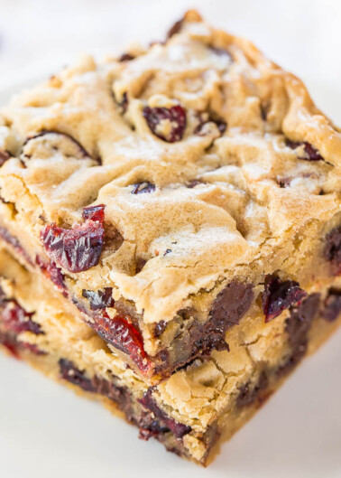 Stack of cranberry chocolate chip blondies on a white plate.