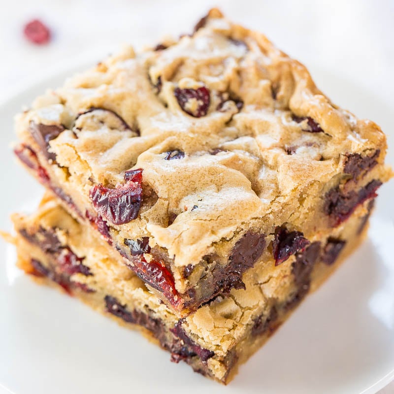 Stack of cranberry chocolate chip blondies on a white plate.