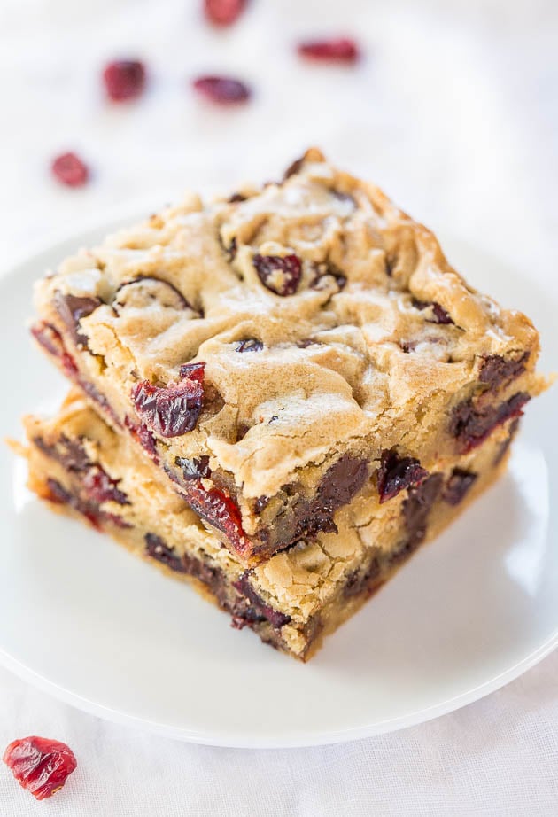 two cranberry bars stacked on a white plate