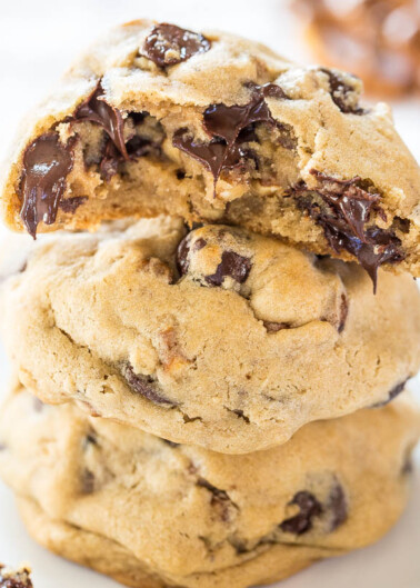 A stack of freshly-baked chocolate chip cookies with melty chocolate visible.