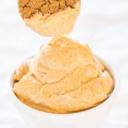 A spoonful of creamy peanut butter being lifted from a bowl, showing a smooth and spreadable texture.