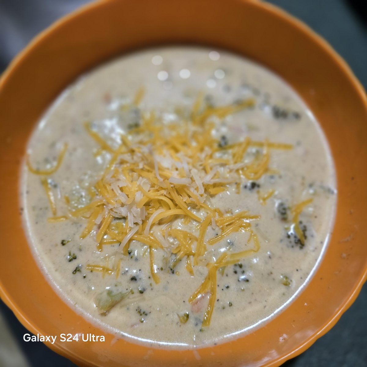 A bowl of creamy soup topped with shredded cheese.
