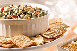A bowl of mixed vegetable salad served with whole grain crackers.