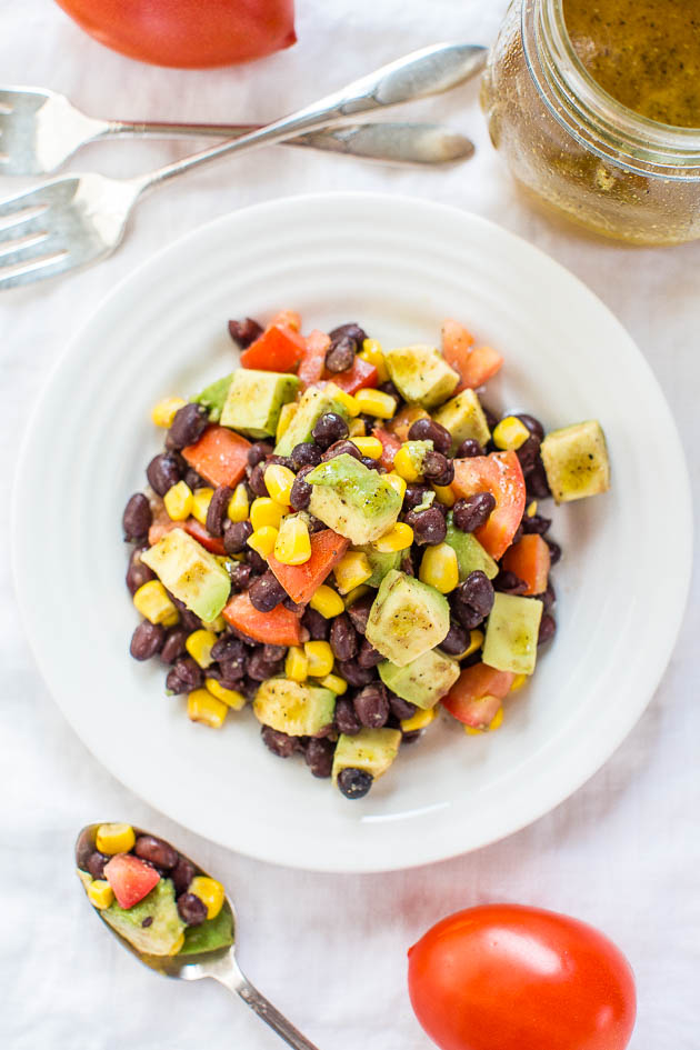 Black Bean Corn Avocado Salad in white bowl next to forks and spoon