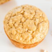 A close-up of a freshly baked oatmeal cookie on a light surface.