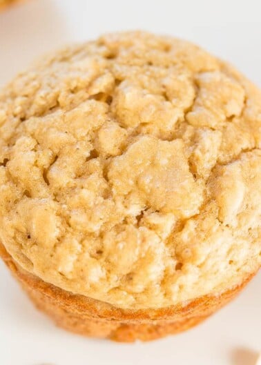 A close-up of a freshly baked oatmeal cookie on a light surface.