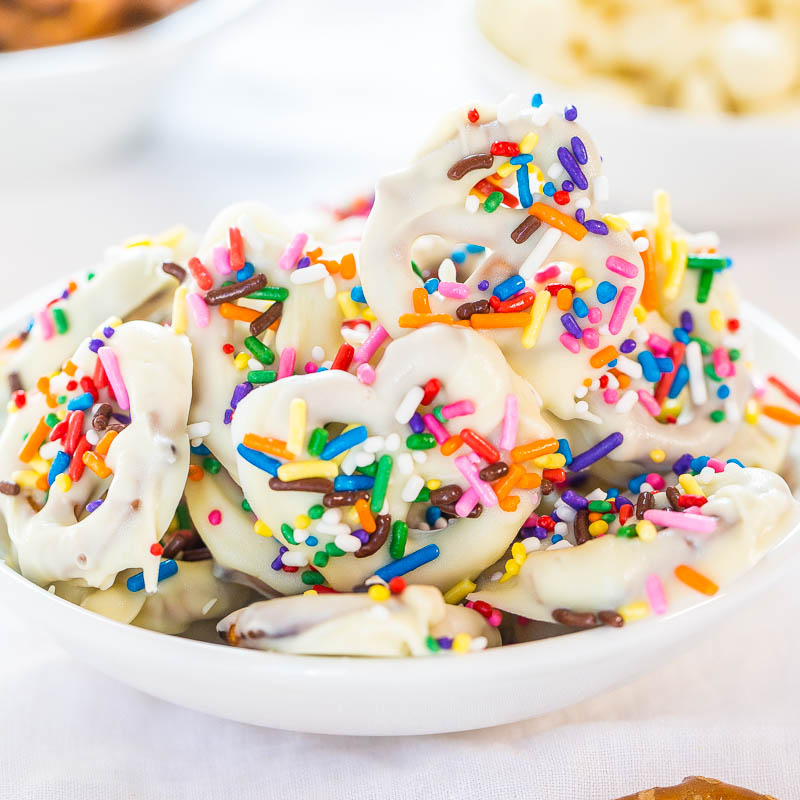 A bowl of white chocolate-covered pretzels garnished with colorful sprinkles.